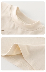 Détail du col côtelé et de la couture sur un pull en maille beige pour bébé