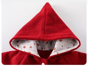Detailed close-up of a red wool hooded cape with white cherry print lining for kids