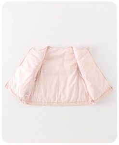 Détail du gilet rose pour enfant avec doublure à carreaux et cordons de serrage à l'ourlet