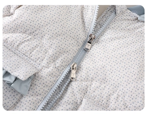 Macro detail of baby romper showing blue floral quilted fabric and double metal zippers
