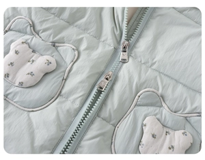Detailansicht der hellgrünen gesteppten Babyweste mit floralen Taschen in Bärenform