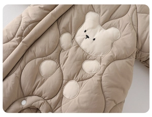 Detail of baby winter romper showing quilted fabric and cute bear embroidery patch