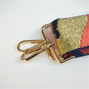 Close-up of golden metal lobster clasp and multicolor woven strap with metallic threads