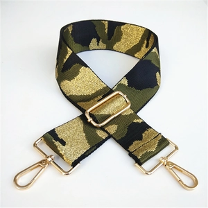 Close-up of wide camouflage woven bag strap with golden metal carabiner hooks