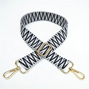 Detail view of the black and white geometric woven strap with golden metal lobster clasps