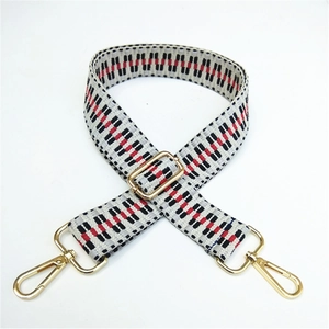 Close-up of adjustable woven purse strap with red black geometric pattern and gold hardware