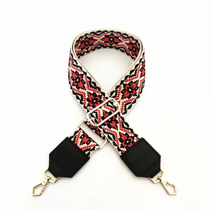 Detail of ethnic geometric bag strap with red and black patterns and gold buckles