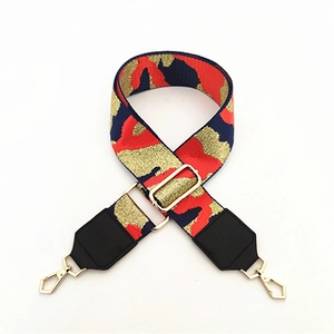 Detail of wide woven strap with abstract camo pattern and golden metal hardware