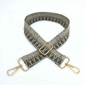 Detail of adjustable wide woven bag strap with green and brown geometric patterns and gold clips