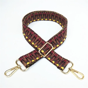 Detail of adjustable woven bag strap with ethnic geometric patterns and gold hardware