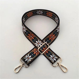 Detalle de correa ancha para bolso con estampado étnico floral y ganchos de metal dorado ajustable
