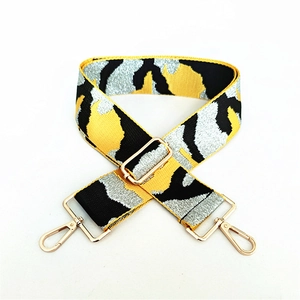 Close-up of camo pattern wide bag strap with gold metal lobster clasps and buckle