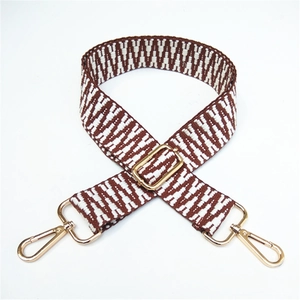 Close-up of ethnic woven pattern bag strap with golden metal hooks and adjustable buckle