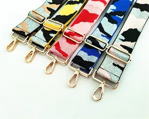 Close-up of wide nylon crossbody strap with colorful camo pattern and golden hooks