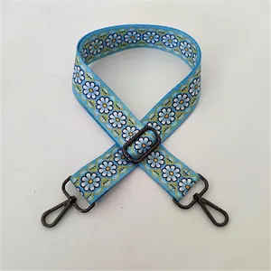 Close-up of wide sky blue fabric bag strap with daisy print and gun-metal clasp