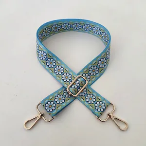 Detail of light blue daisy pattern bag strap with adjustable gold swivel hooks
