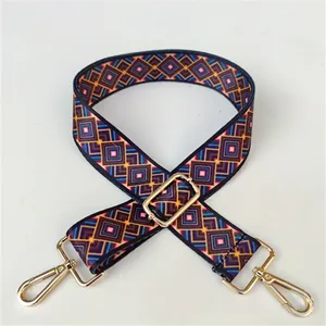 Close-up of geometric woven strap with gold metal swivel hooks and adjustment buckle