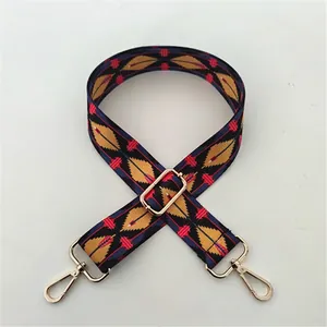 Detail view of geometric ethnic style bag strap with gold metal hooks and adjustable buckle