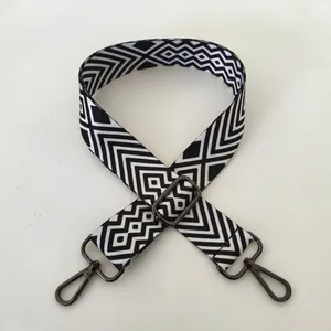 Close-up of black and white geometric patterned bag strap with gunmetal lobster clasps