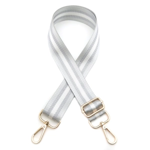 Close-up of adjustable striped handbag strap with polished gold hardware buckles