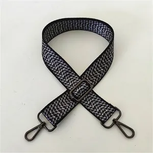 Detailed view of black and white woven strap with gunmetal swivel clasps and buckle