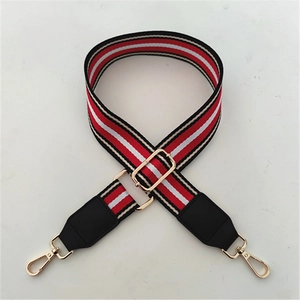 Detail view of the red and white striped wide bag strap with golden lobster clasps