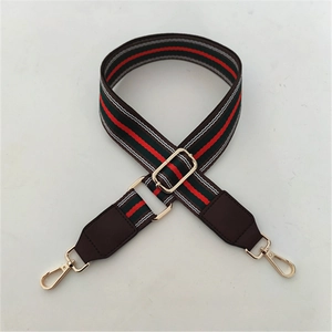 Detail of red and green striped woven strap with dark brown leather ends and gold metal clips