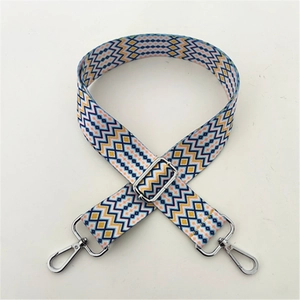 Detail view of woven bag strap with blue and yellow wave patterns and silver lobster clasps