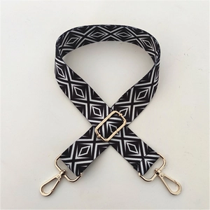 Detail of adjustable shoulder strap with black and white geometric pattern and gold hardware