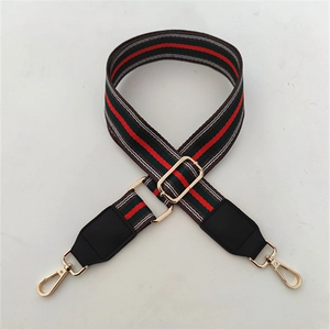 Detail of adjustable canvas strap with red and green stripes and gold hardware