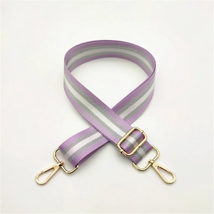Close-up of adjustable purple and grey striped woven bag strap with gold metal hooks