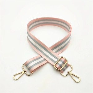 Detail of adjustable pink and grey striped woven bag strap with gold metal buckles