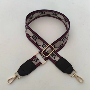 Detail of adjustable woven handbag strap with monogram pattern and metal lobster clasp