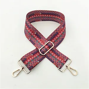Close-up of bohemian red woven bag strap with blue geometric patterns and gold metal buckles