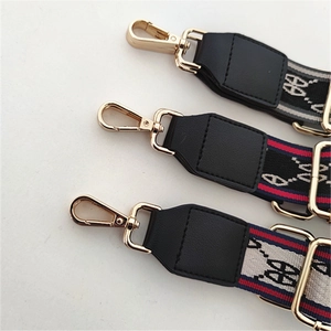 Close-up of adjustable striped handbag straps with gold metal clasps and leather ends