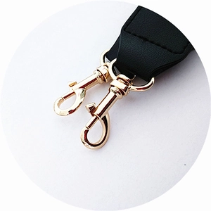 Close-up of golden lobster clasps and black leather ends of the adjustable bag strap
