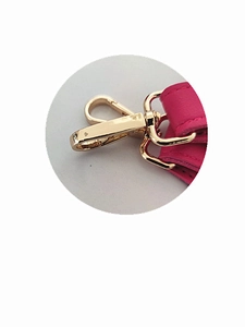Detail of rose pink leather bag strap with polished gold lobster clasp and heart logo