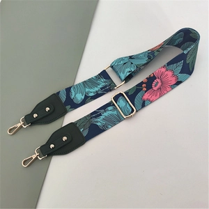 Close-up of floral wide bag strap with navy background and golden metal hardware
