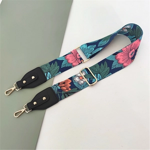 Detail of colorful floral polyester bag strap with golden metal hooks and leather ends