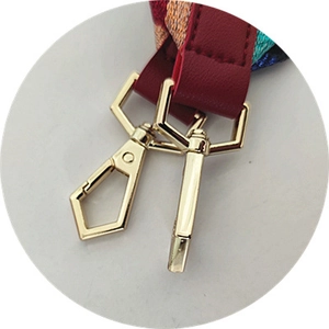 Detail of golden swivel hooks with red leather and colorful ethnic style woven strap