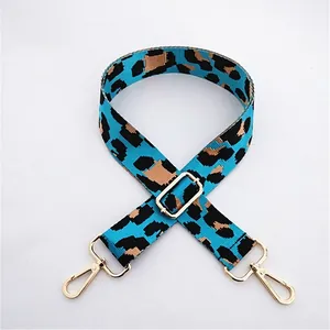 Close-up of light blue leopard print bag strap with golden metal swivel hooks and buckle