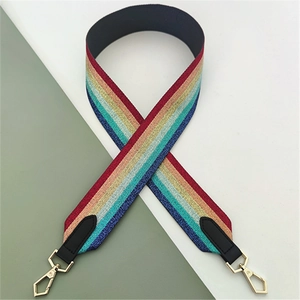 Detail of colorful striped woven bag strap with black leather ends and gold metal clasps