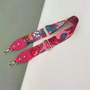 Detail showing tropical floral pattern on wide fabric bag strap with golden lobster hooks