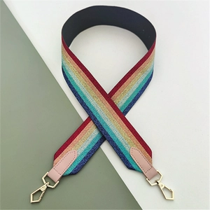 Close-up of rainbow ethnic style bag strap with pink leather ends and gold metal lobster clasps