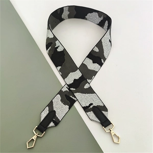 Macro shot of stylish camouflage bag strap with black leather ends and golden metal hooks
