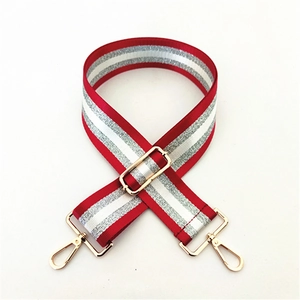 Close-up of adjustable striped wide bag strap with gold metal hooks and sliding buckle