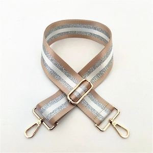Detail of adjustable wide bag strap with khaki silver stripes and gold metal buckles