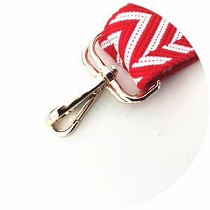 Detail of red and white wave pattern woven strap with polished gold metal hook clasp