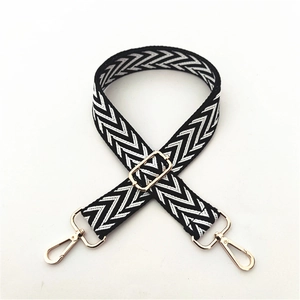 Detail of adjustable black and white herringbone patterned bag strap with gold metal buckles