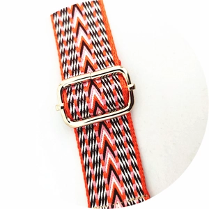 Close-up of ethnic colorful woven bag strap with orange V-pattern and gold metal buckle
